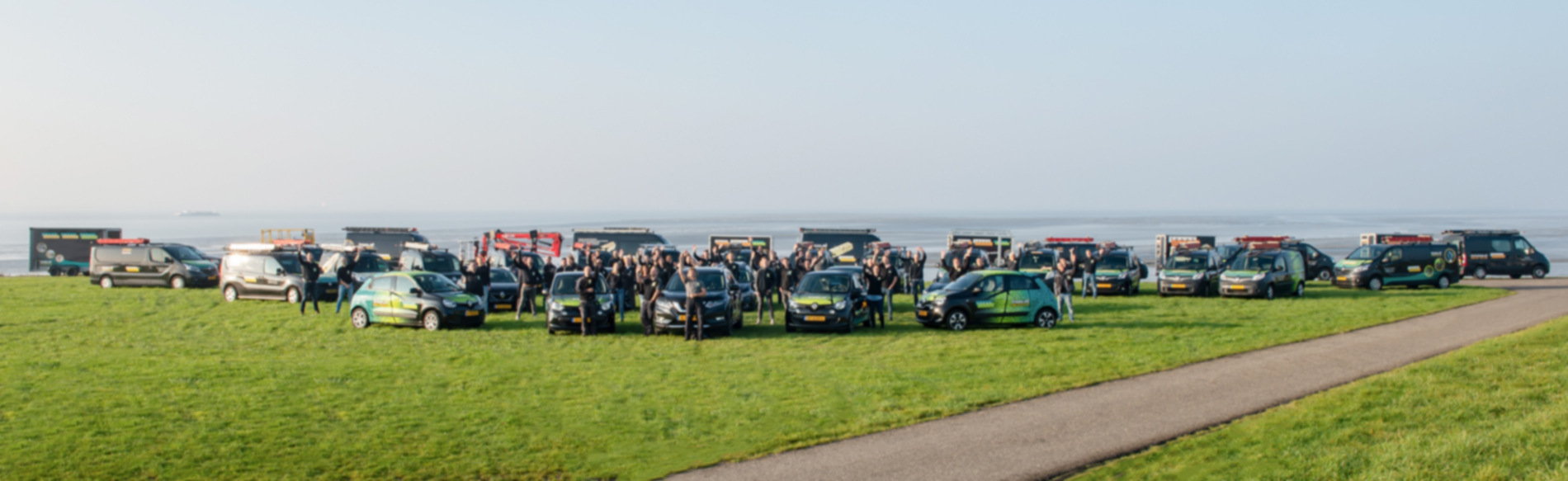 bedrijfsauto's bij elkaar met personeel leden er tussen